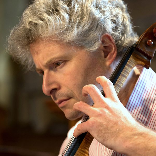 Close up of Robert Max mid-performance, playing a cello.