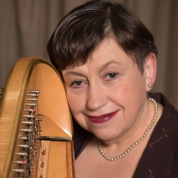 Sioned Williams smiling, holding a harp column.