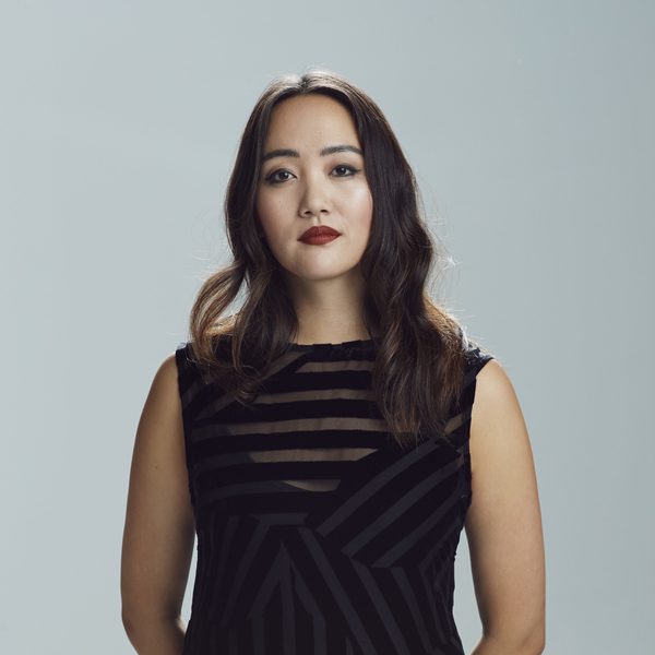 Somi Kim smiles to camera against a grey background.
