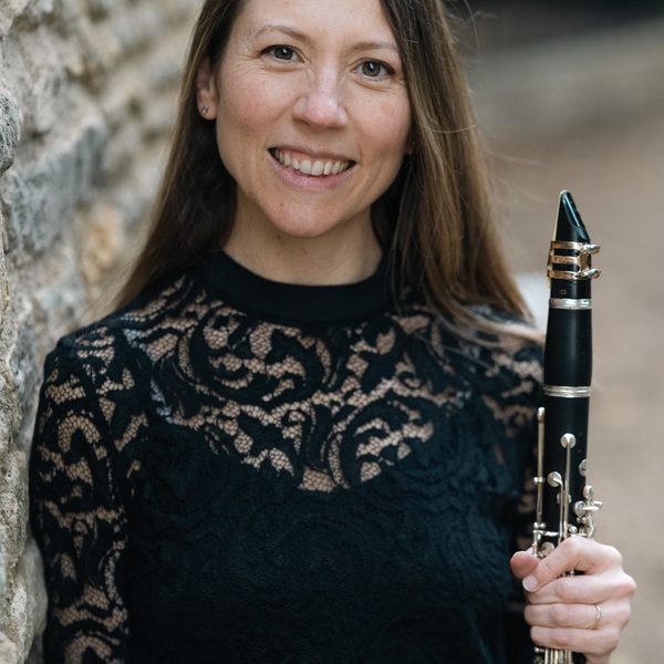 Sonia Sielaff poses for headshot outside, holding a clarinet.
