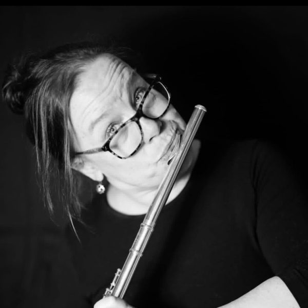 Susan Torke plays a flute, looking to camera.