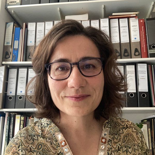 Susana Caldera smiles in front of a tall shelf of folders.