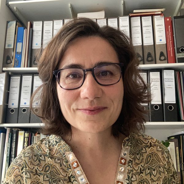 Susana Caldera smiles in front of a tall shelf of folders.