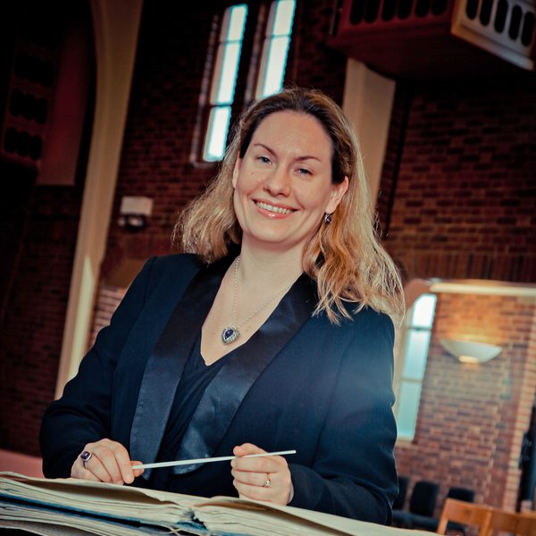 Tansy Castledine sits at a desk, smiling to camera.