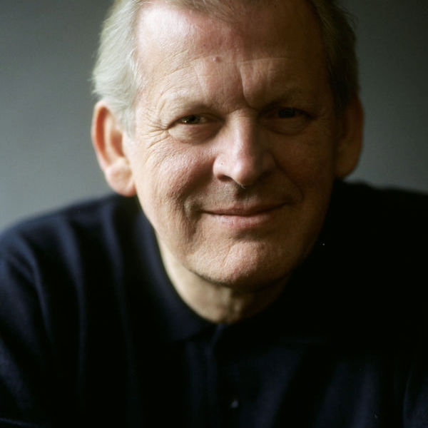 Thomas Allen smiles to camera with hands clasped