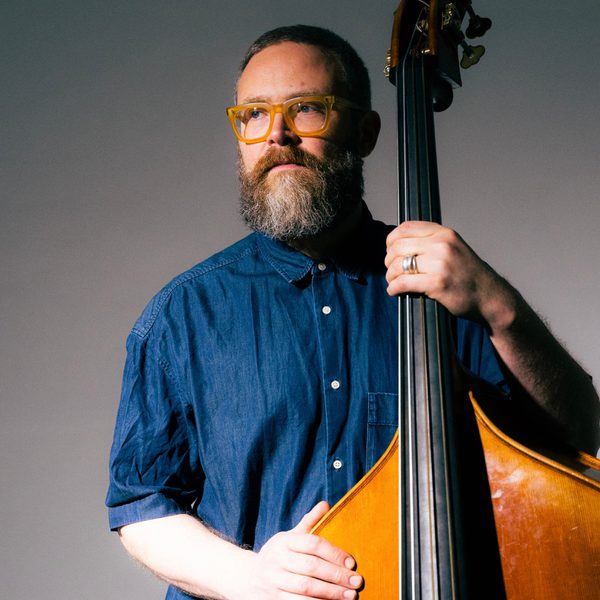 Tom Herbert holding a double bass neck, looking off camera.