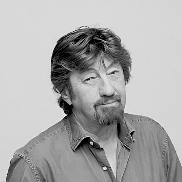 Portrait of Trevor Nunn smiling to camera against cream background (by Joel Redman).