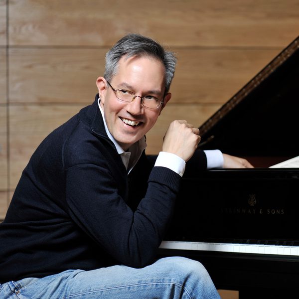 William Fong sits at a piano, looking off camera.