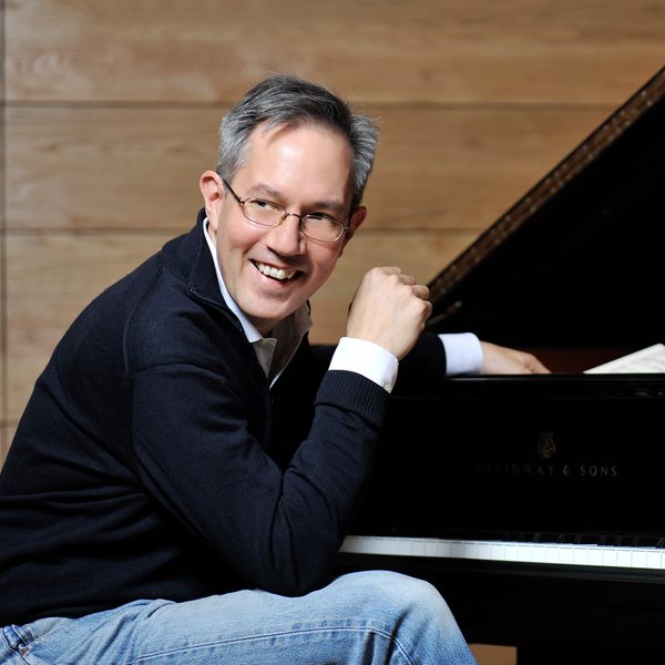 William Fong sits at a piano, looking off camera.