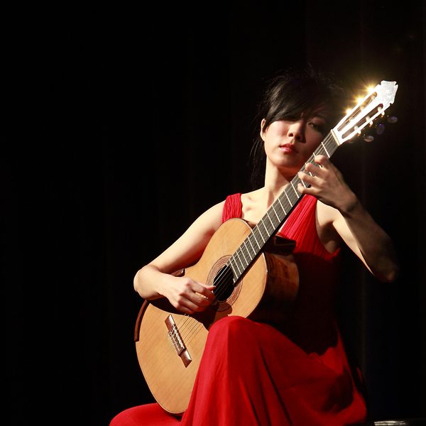 Xuefei Yang plays a guitar in a red dress.