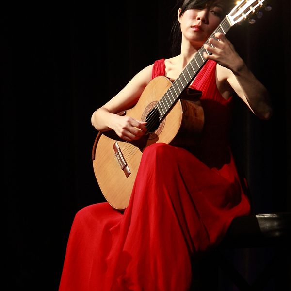 Xuefei Yang plays a guitar in a red dress.