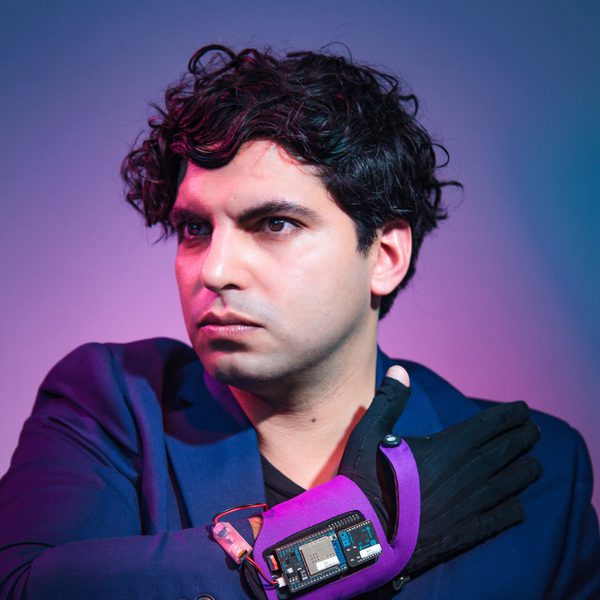 Zubin Kanga looks off-camera, wearing an electronic device on wrist.