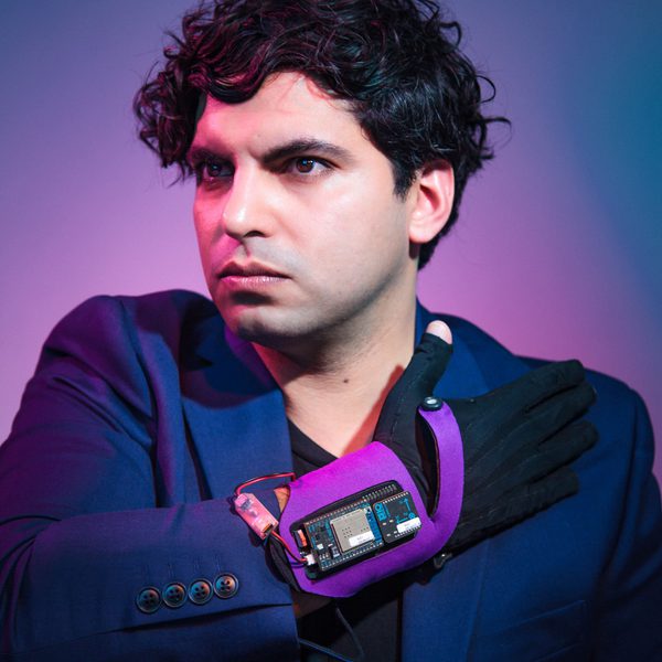 Zubin Kanga looks off-camera, wearing an electronic device on wrist.