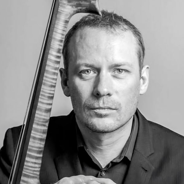 Portrait of Graham Mitchell facing camera, with double bass leaning against shoulder